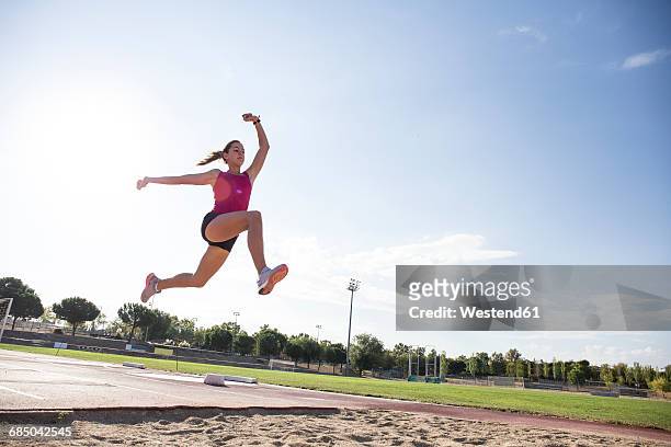 female long jumper mid-air - long jumper stock pictures, royalty-free photos & images