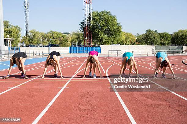 female runners on tartan track in starting position - estadio de atletismo fotografías e imágenes de stock