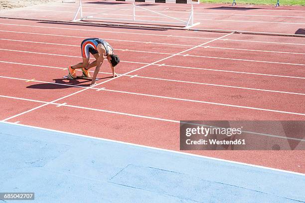 runner on tartan track in starting position - tartanbahn stock-fotos und bilder