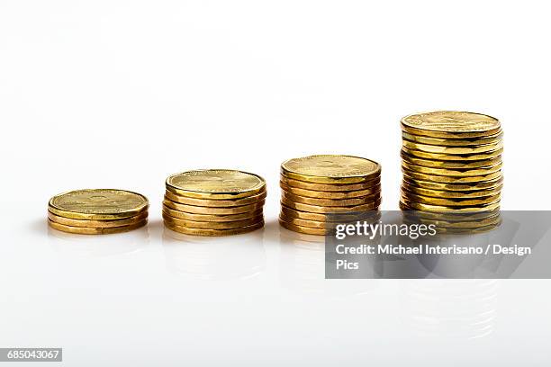 close up of a row of stacked coins (loonies) on a white background, getting higher on each stack - loonie stock pictures, royalty-free photos & images