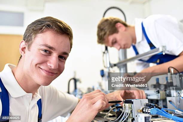 portrait of smiling student working with pneumatics component parts - mechatronics stock-fotos und bilder
