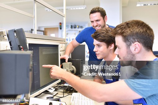 Technical instructor and students looking at computer screen Technical instructor and students looking at computer screen