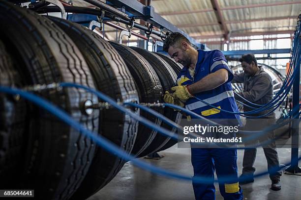 two tire repairmen filling up air in tire valves - inflar fotografías e imágenes de stock