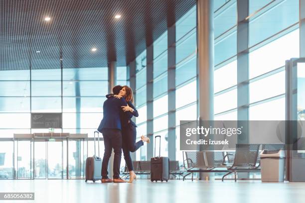 businessman hugging a young woman at the airport terminal - introducing boyfriend stock pictures, royalty-free photos & images