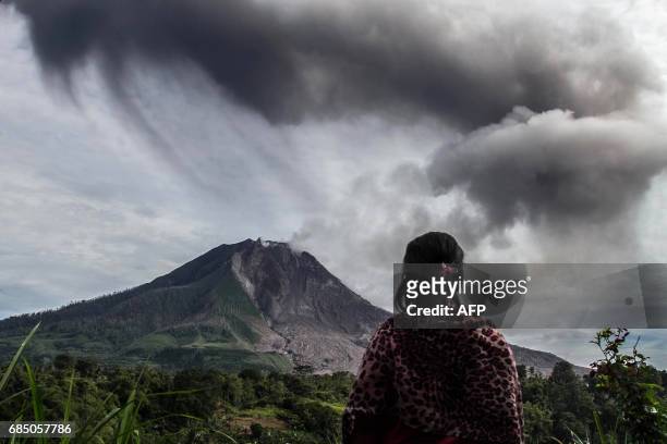Villager looks on as Mount Sinabung volcano spews thick volcanic ash, as seen from Beganding village in Karo, North Sumatra province, on May 19,...