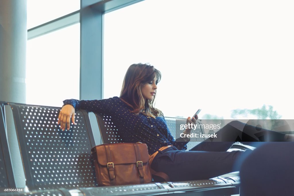 Jeune femme attend son vol au salon d’aéroport