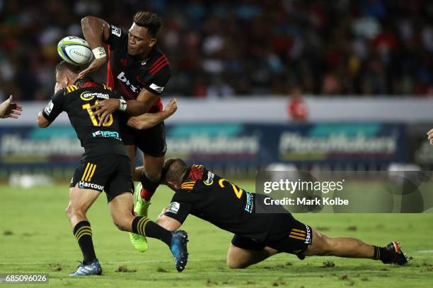 Seta Tamanivalu of the Crusaders passes as he is tackled by Aaron Cruden and Nathan Harris of the Chiefs during the round 13 Super Rugby match...