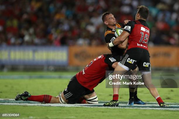 Aaron Cruden of the Chiefs is tackled by Sam Whitelock and David Kaetau Havili of the Crusaders during the round 13 Super Rugby match between the...