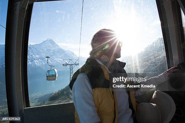 woman rides cable car down mountain slop - seilbahn stock-fotos und bilder