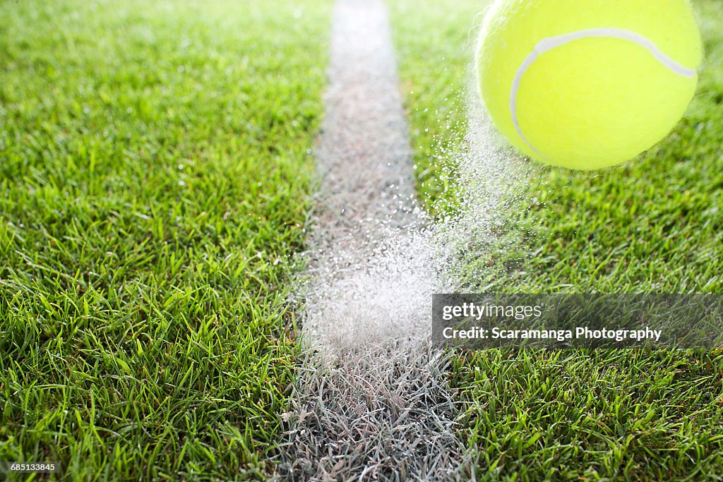 Close up of tennis ball hitting chalk line
