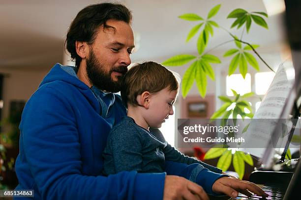 father and son playing piano. - playing music together stock-fotos und bilder