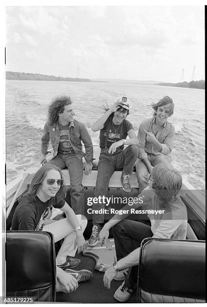 Steve Smith, Neal Schon, Steve Perry, Jonathan Cain, and Ross Valory of the rock band Journey ride in a boat.