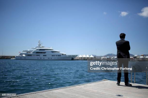 Man looks out over luxury yachts berthing next to the Palais de Festivals as owners and movie company's chartering the yachts attend the Cannes Film...
