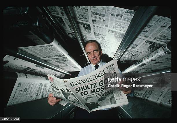 Publishing magnate Rupert Murdoch at the printing presses of the New York Post. He is reading a copy of the newspaper, whose headline declares...