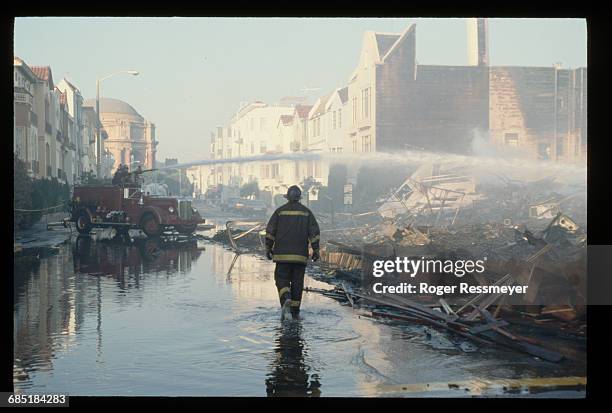 Firefighters spray the ruins of fallen houses with water the day after the Loma Prieta earthquake.