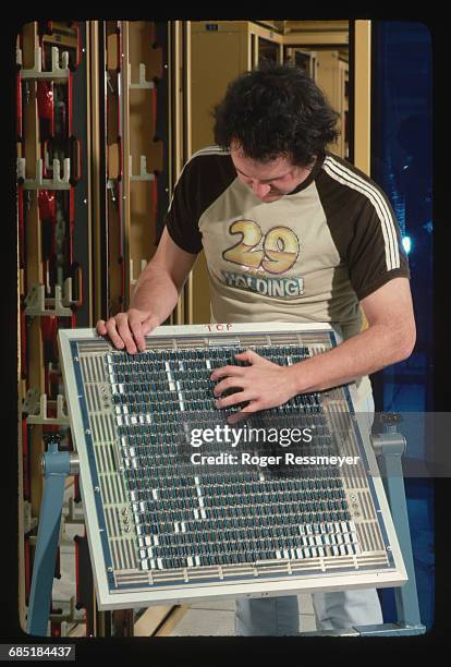 Computer engineer John Zugel carries circuit board, as he and a colleague assemble a Cray supercomputer support frame.