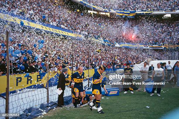 Diego Maradona enters the field for an Argentina soccer championship match against San Lorenzo as fans toss confetti from the stands.