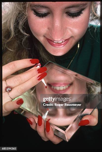 Woman squeezes out a bit of Ener-B, a vitamin B-12 gel, onto a mirror. The gel is inhaled through the nose and supposedly gives more energy, however,...