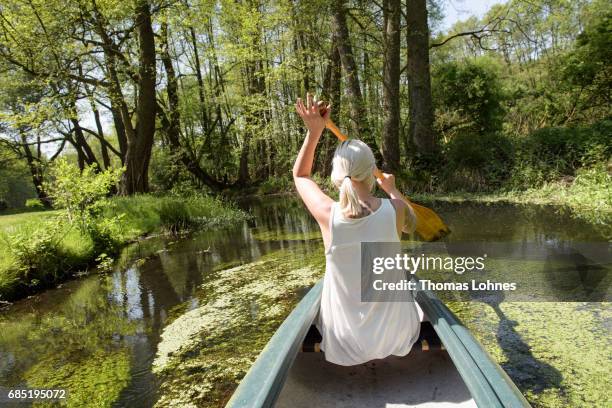 Young woman paddles a canoe on the creek 'Loecknitz' in Brandenburg state on May 19, 2017 near Erkner, Germany. Brandenburg, with its multitude of...