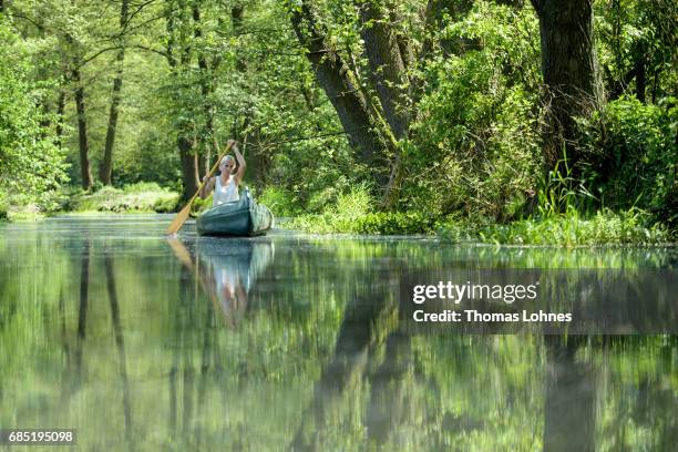 Young woman paddles a canoe on the creek 'Loecknitz' in Brandenburg state on May 19, 2017 near Erkner, Germany. Brandenburg, with its multitude of...