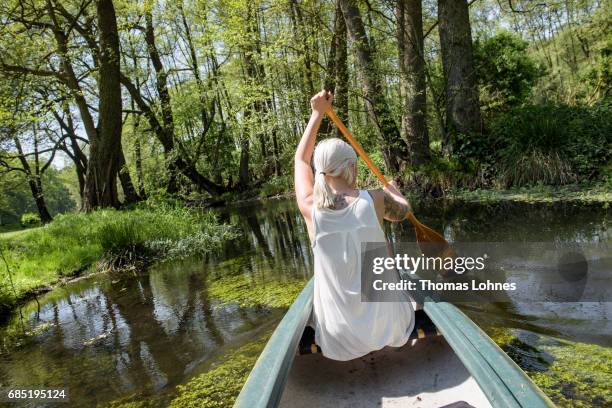 Young woman paddles a canoe on the creek 'Loecknitz' in Brandenburg state on May 19, 2017 near Erkner, Germany. Brandenburg, with its multitude of...