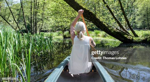 Young woman paddles a canoe on the creek 'Loecknitz' in Brandenburg state on May 19, 2017 near Erkner, Germany. Brandenburg, with its multitude of...