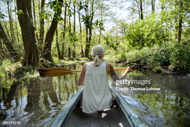 Young woman paddles a canoe on the creek 'Loecknitz' in Brandenburg state on May 19, 2017 near Erkner, Germany. Brandenburg, with its multitude of...