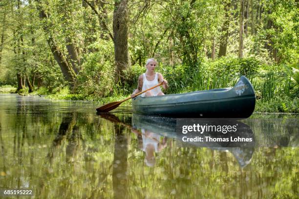 Young woman paddles a canoe on the creek 'Loecknitz' in Brandenburg state on May 19, 2017 near Erkner, Germany. Brandenburg, with its multitude of...