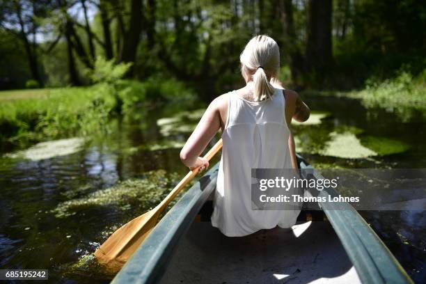 Young woman paddles a canoe on the creek 'Loecknitz' in Brandenburg state on May 19, 2017 near Erkner, Germany. Brandenburg, with its multitude of...