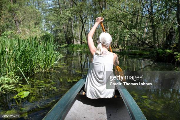 Young woman paddles a canoe on the creek 'Loecknitz' in Brandenburg state on May 19, 2017 near Erkner, Germany. Brandenburg, with its multitude of...