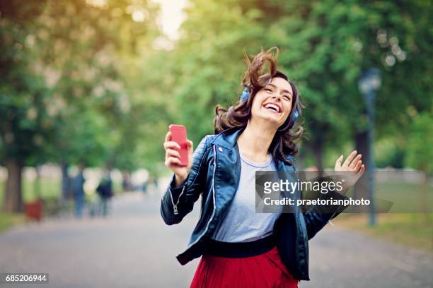 young girl is dancing and listening the music till walking in the park - listening stock pictures, royalty-free photos & images