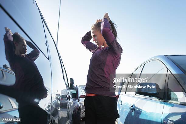 young woman preparing to workout between cars - cars on a road sunny photos et images de collection