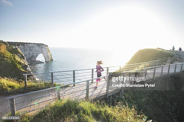 woman running on cliffs at sunset, france - sea cliff bridge stockfoto's en -beelden