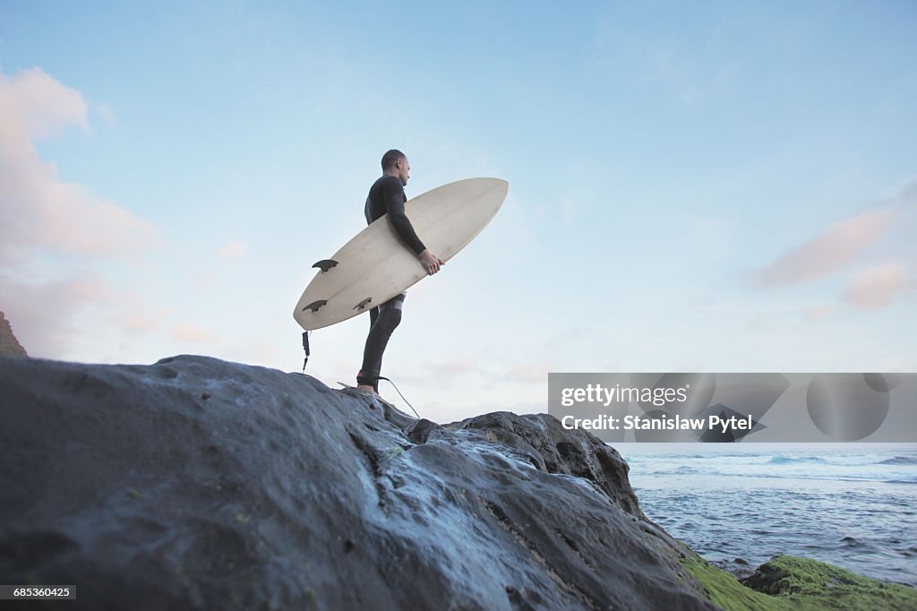 Surfer standing on rock