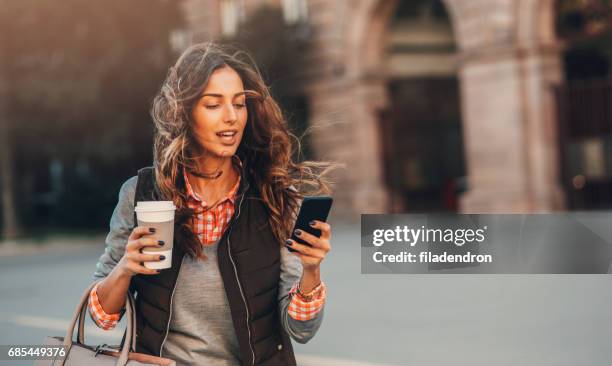 vrouw texting en drinken koffie buiten. - mobiliteit stockfoto's en -beelden