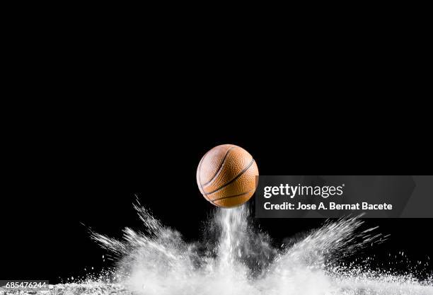 impact and rebound of a ball of basketball on a surface of land and powder on a black background - driblar deportes fotografías e imágenes de stock