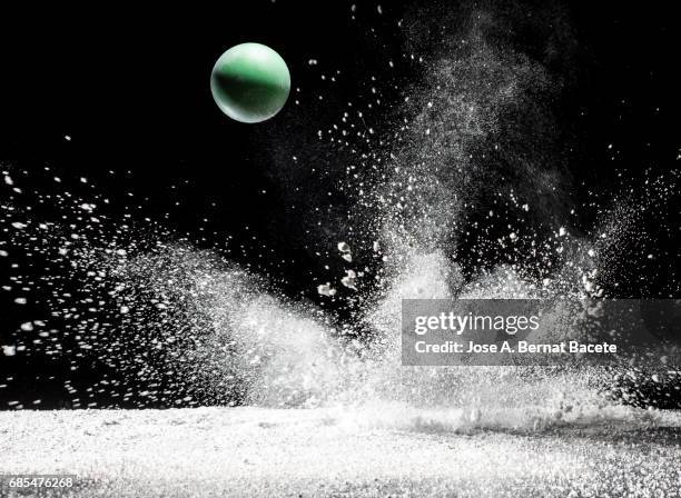 impact and rebound of a ball  on a surface of land and powder on a black background - saltar para cima e para baixo imagens e fotografias de stock