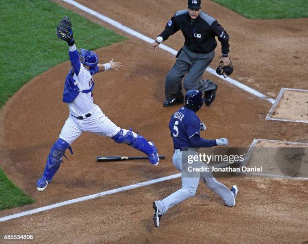 Willson Contreras of the Chicago Cubs leaps in vain to try to catch a relay throw as Jonathan Villar of the Milwaukee Brewers moves in score a run in...