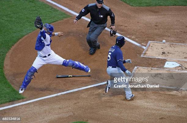 Willson Contreras of the Chicago Cubs leaps in vain to try to catch a relay throw as Jonathan Villar of the Milwaukee Brewers moves in score a run in...