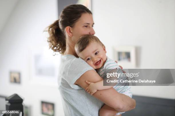 a 8 months old baby in the arms of his mum - mom baby stock pictures, royalty-free photos & images