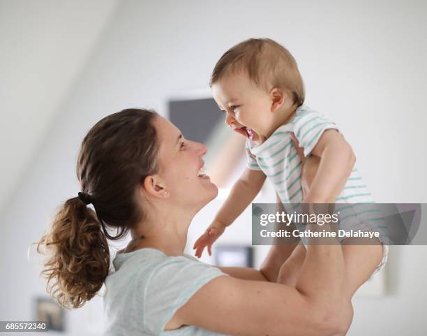 a 8 months old baby in the arms of his mum - bébé joue photos et images de collection