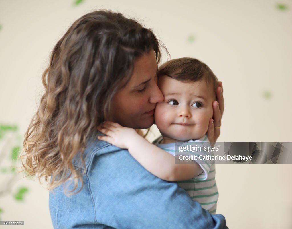 A 8 months old baby in the arms of his mum