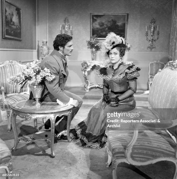 Romanian actress Nadia Gray sitting on a sofa, meets Fausto Tozzi italian actor in role of composer Gaetano Doninzetti. Film Casta Diva, directed by...