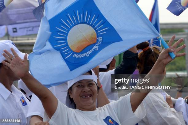 Supporter of Cambodia National Rescue Party holds a party flag during the Commune Election Campaign in Phnom Penh on May 20, 2017. Tuk-tuks blaring...