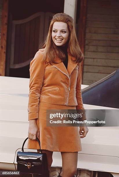 Italian born actress Ira von Furstenberg pictured wearing a matching orange velvet jacket and skirt suit during production of the comedy film...