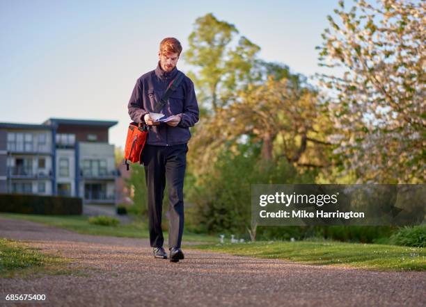 postman walking through urban park on postal round - postal worker stock pictures, royalty-free photos & images