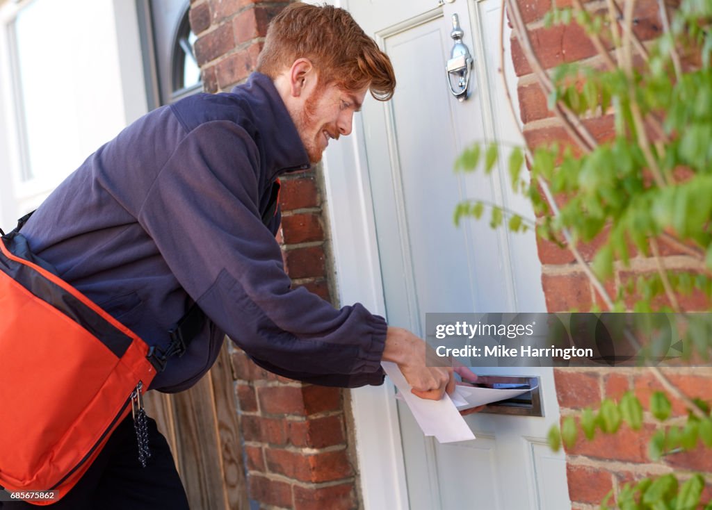 Postman posting letters through resident's door