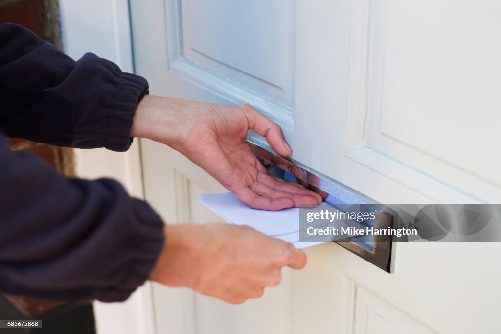 Close up of postman delivering letters