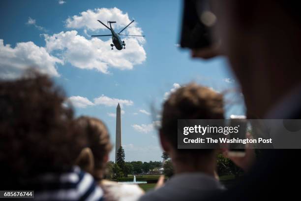 People watch as Marine One, with President Donald Trump and first lady Melania Trump aboard, lifts off from the South Lawn for a short trip to...