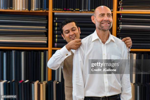 man krijgt gemeten voor een op maat gemaakte pak in een winkel van de kleermaker - made to measure fashion stockfoto's en -beelden